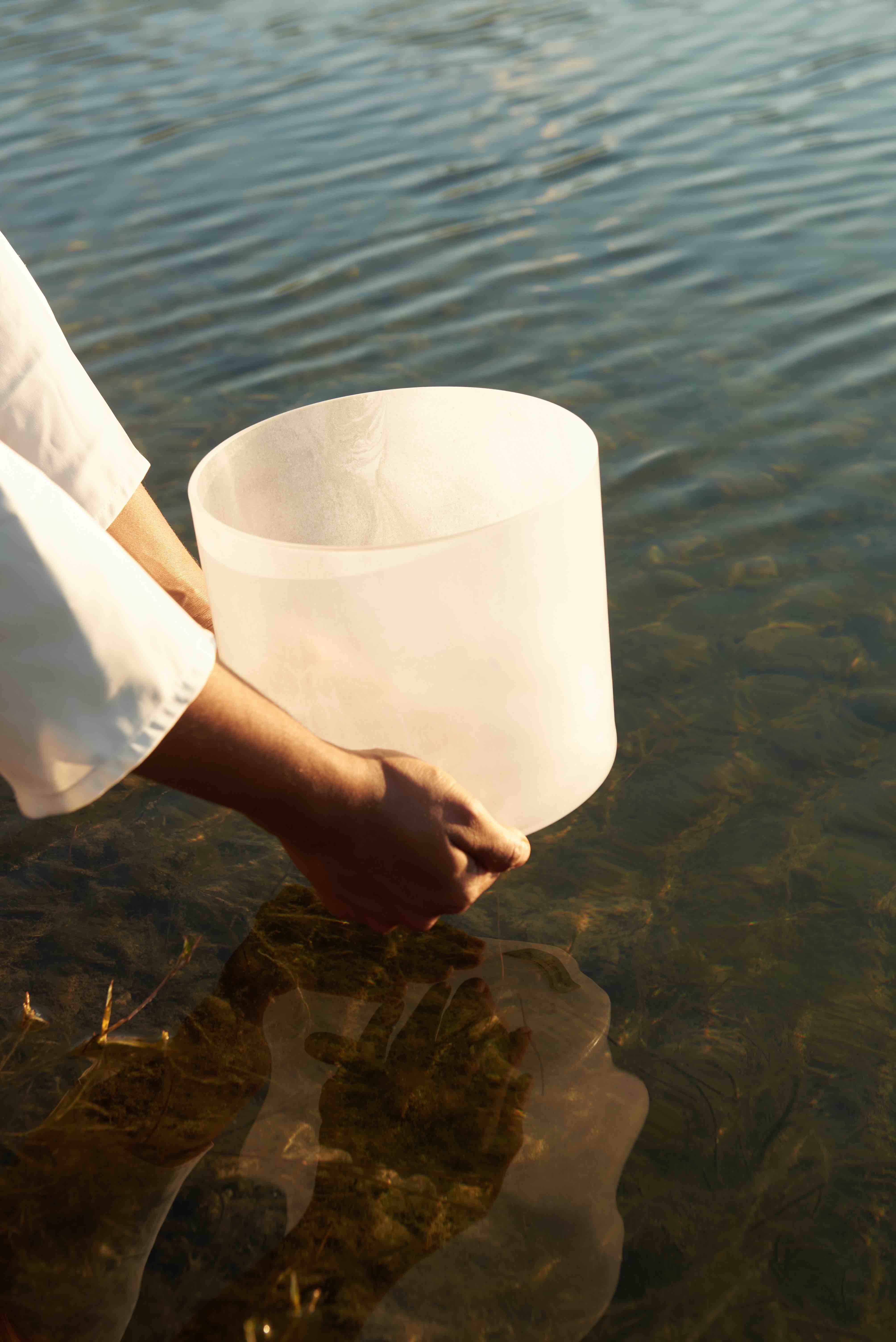 hands holding soundbowl near lake