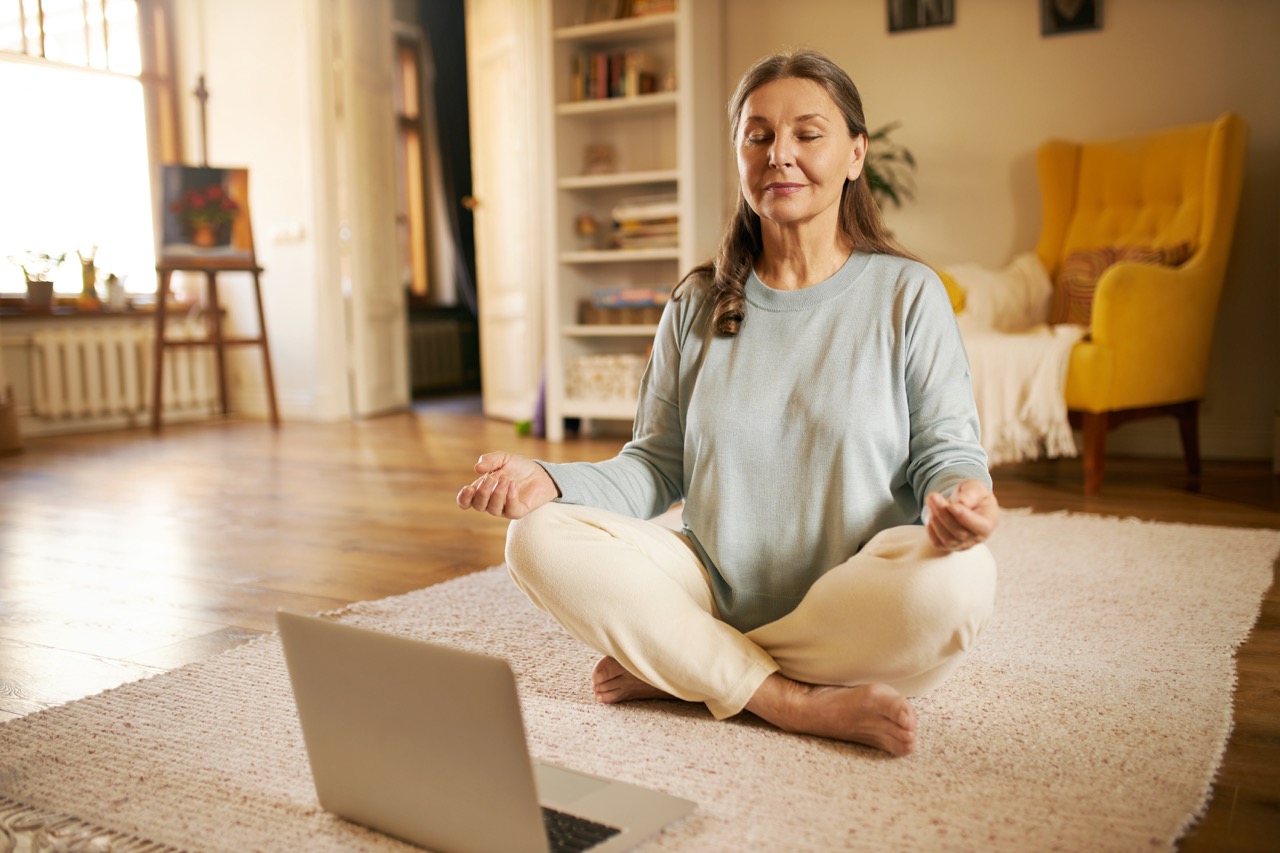 elder women meditating with laptop